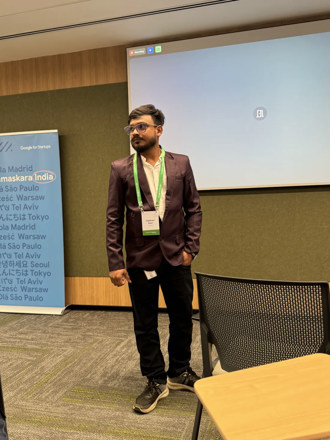Siddhant Gour in a purple blazer in front of the presentation screen at the Gemini API Sprint